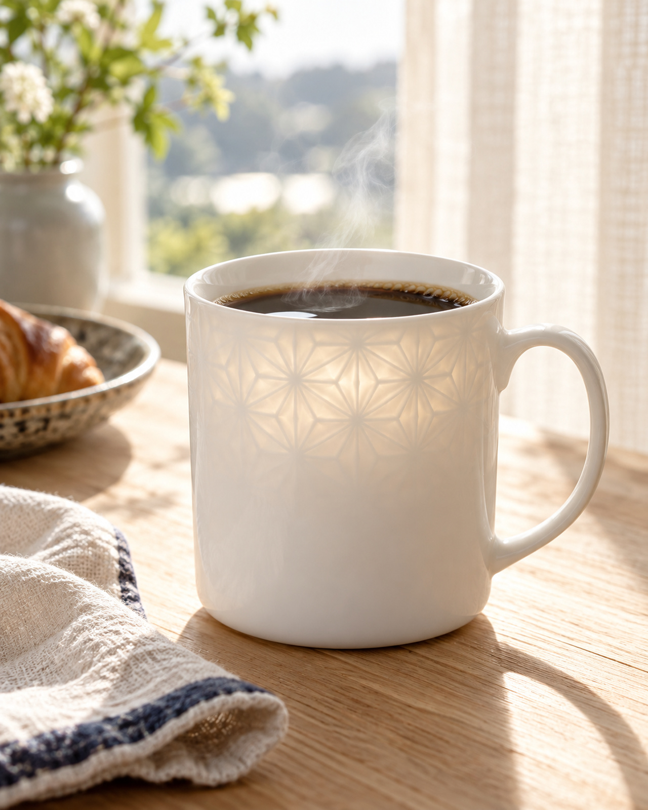 朝のテーブルに置かれたコーヒー入りの白磁マグ
